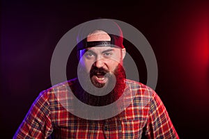 Angry expressive bearded hipster man on black background