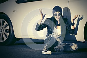 Angry fashion punk woman sitting next to her car photo