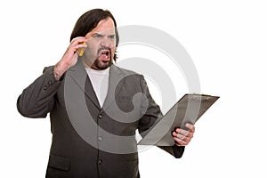 Angry fat Caucasian businessman talking on mobile phone while ho