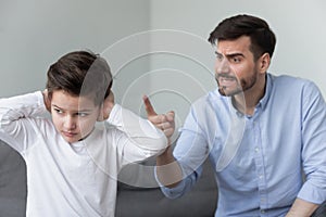 Angry father shouting at stubborn fussy little son closing ears photo