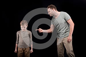 Angry father threatening and gesturing to scared little son