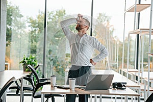 Angry, feeling tired and bad. Man in formal clothes is working in the modern office