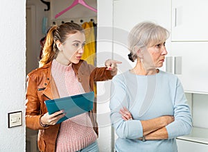 Angry female householder demanding older woman to pay off debt