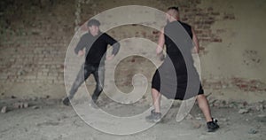 Angry fighting of two men in abandoned building. Athlete uses combat reception