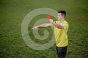 Angry football referee showing a red card and pointing with his hand on penalty