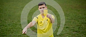 Angry football referee showing a yellow card and pointing with his hand on penalty