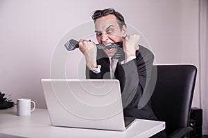 Angry and frustraded business man eating his tie in the office