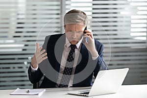 Angry frustrated businessman talking on phone solving business problem