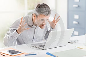 Angry frustrated office worker having problems with his laptop and connection, computer problems and troubleshooting concept photo