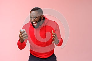 Angry furious african-american bearded guy lose control emotions shouting outraged annoyed smartphone display look phone