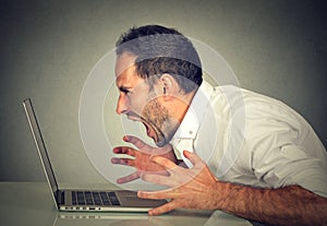 Angry furious business man screaming at computer