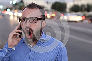 Angry furious businessman on cell phone call yelling and screaming in city