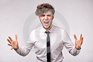 Angry furious businessman shouting out loud with hands up over gray background