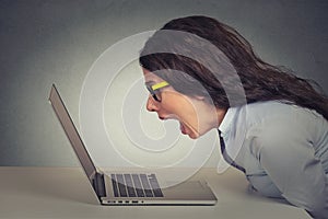 Angry furious businesswoman working on computer, screaming