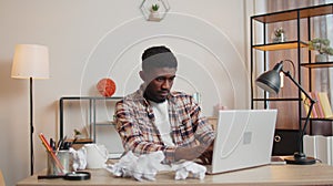 Angry furious man working at home office with crumpled paper, having nervous breakdown at work