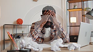 Angry furious man working at home office throwing crumpled paper, having nervous breakdown at work