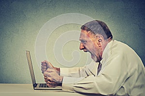 Angry furious senior business man working on computer, screaming
