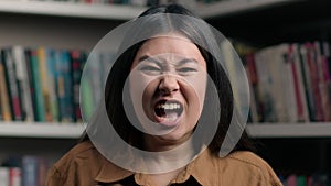 Angry furious stressed asian woman shouting irritated emotion in university library korean girl female student shout