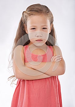 Angry, girl and child in studio with arms crossed, frustrated in portrait and emotion, cross or upset on white