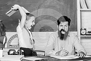 Angry girl hates reading book. back to school. Private teaching. small girl child with bearded teacher man in classroom