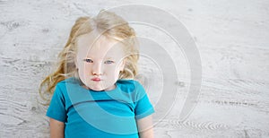 Angry girl lying on white wooden floor