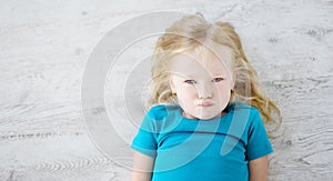 Angry girl lying on white wooden floor