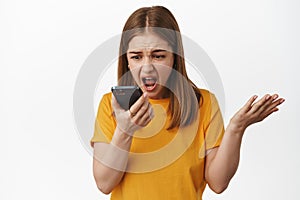 Angry girl shouting at smartphone voice message, talk on speakerphone and screaming at mobile phone dynamic, shaking