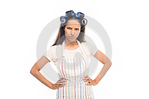 Angry housewife with curlers standing with hands on hips,