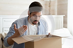 Angry irritated man unboxing parcel, wrong or broken order