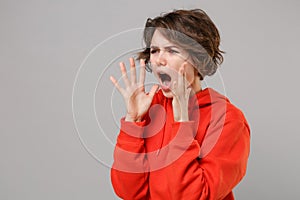 Angry irritated young brunette woman girl in casual red hoodie posing isolated on grey wall background in studio. People