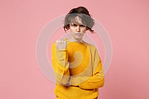 Angry irritated young brunette woman girl in yellow sweater posing isolated on pastel pink wall background in studio