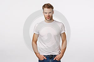 Angry, judgemental handsome macho blond male model in white t-shirt, look offended or angry, squinting aggressive photo