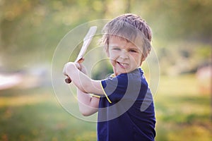 Angry little boy, holding sword, glaring with a mad face at the