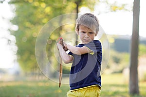 Angry little boy, holding sword, glaring with a mad face at the photo