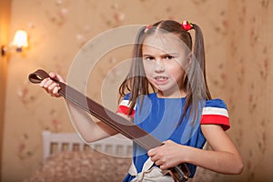 Angry little girl with belt in hand.