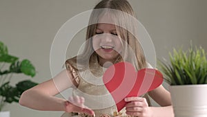 Angry little girl cutting red paper heart, heartbreak and heartache concept for Valentines Day