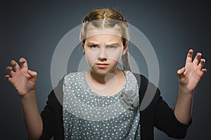 Angry little girl on gray background.