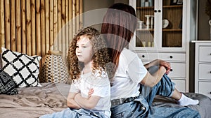 Angry little girl with long loose curly hair crosses hands