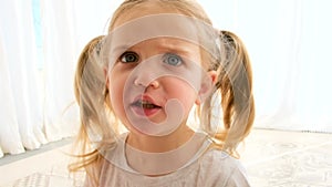 Angry little girl with pigtails in t-shirt shouts to camera