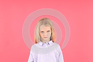 Angry little girl in shirt on pink background