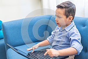 Angry little latin boy using a laptop