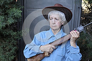 Angry looking senior woman holding a weapon