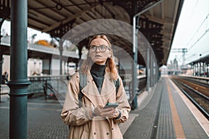 Angry lost woman waiting on the station platform and using smart phone at the airport link station, Gdansk, Poland.
