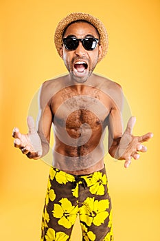 Angry mad african man in swimwear standing and shouting
