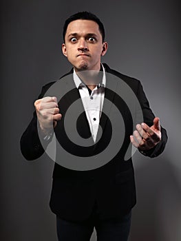 Angry mad business man fighting and gesturing  the fist and on grey background. Closeup