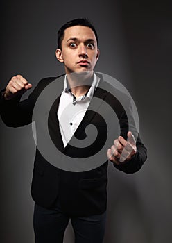 Angry mad business man fighting and gesturing  the fist and on grey background. Closeup