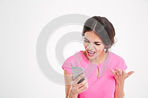 Angry mad young woman shouting and using mobile phone photo