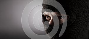 Angry man in a balaclava on a dark background photo