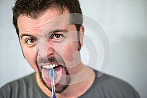 Angry man brushing his tongue