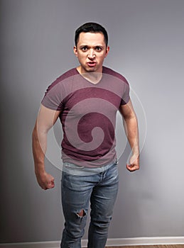 Angry man in casual t-shirt and blue jeans with negative emotion looking with fists